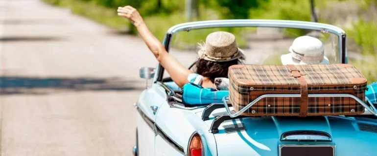 Two people driving in a classic car