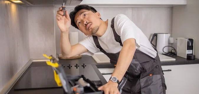 Handyman using screwdriver to fix oven hood