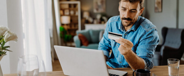 Young man using his credit card as he shops on a laptop