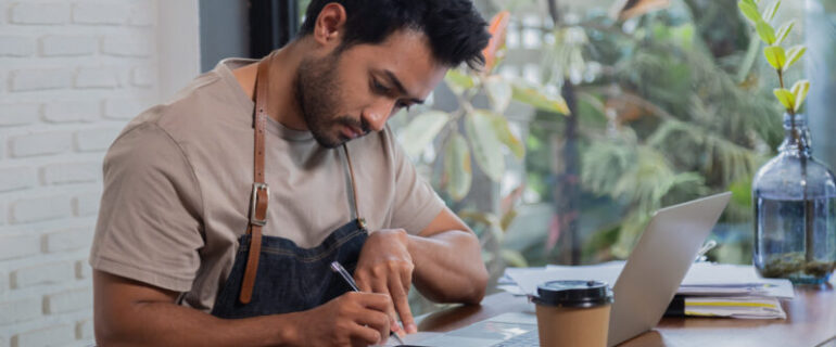 The owner of a coffee shop sits at his laptop at a table in his shop after hours